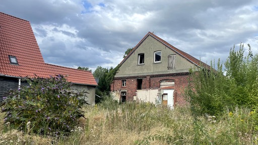 Ein altes Gebäude steht auf einer brachen Fläche.