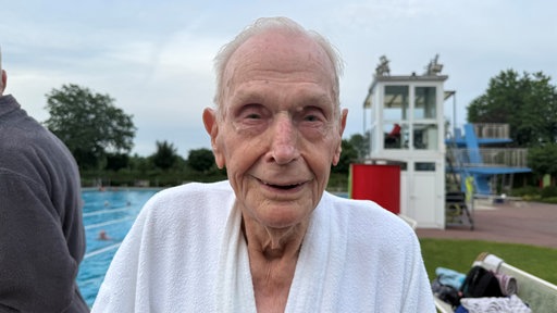 Der 100-jährige Willi steht am Beckenrand im Freibad 