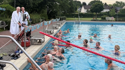 Der 100-jährige Willi steht am Beckenrand im Freibad, seine Geburtstagsgäste sind bereits im Wasser