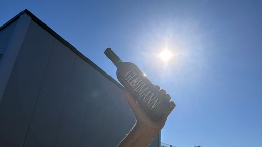 Eine Glüweinflasche wird gegen die Sonne gehalten