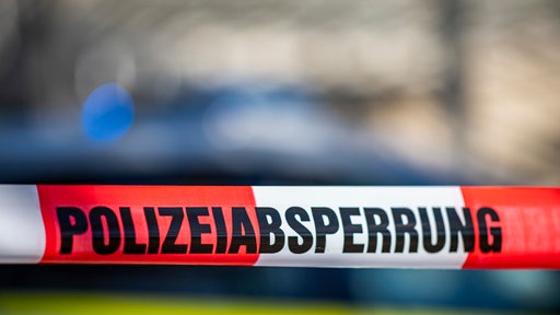Eine Polizeiabsperrung vor Blaulicht