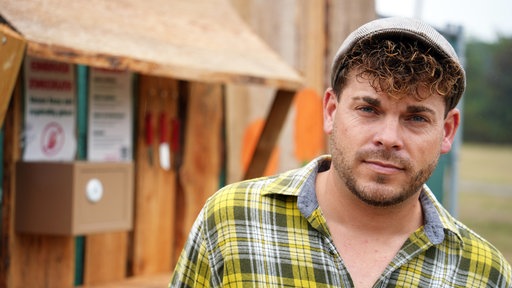 Ein Mann mit lockigen Haaren und einer Mütze