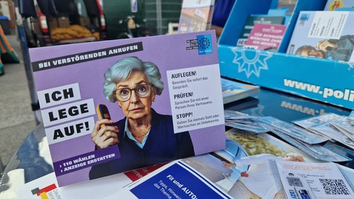 Eine Karte mit einer älteren Frau und der Aufschrift "Ich lege auf" warnt vor Telefonbetrug.