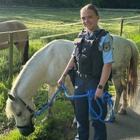 Polizistin steht neben dem entlaufenden Pony