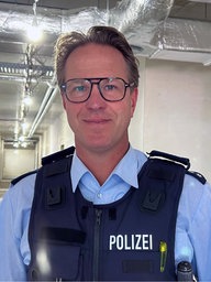 Ein Polizist lächelt in die Kamera.