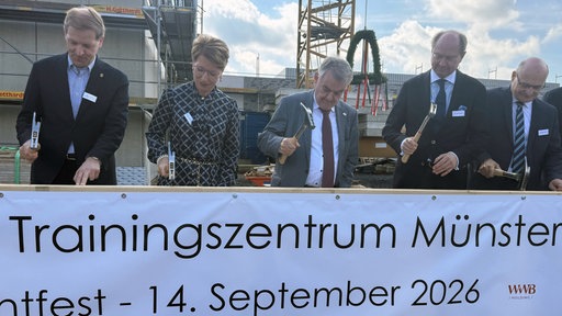 Reul und andere schlagen das Schild des Trainingszentrums feierlich fest.