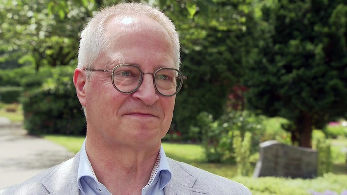 Ein Mann steht auf einem Friedhof 