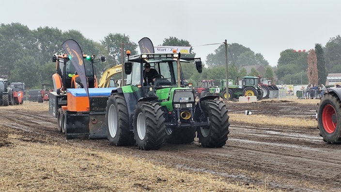 Ein Trecker zieht einen Hänger über ein Feld
