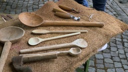 Unterschiedliche Holzlöffel liegen auf einer Matte.