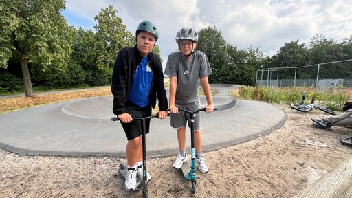 Die ukrainischen Jungs David und Artur mit Helmen und ihren Tretrollern.