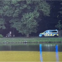 Zwei Menschen sitzen auf einem Motorroller und fliehen vor einem Polizeiwagen.