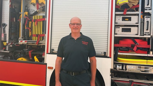 Ein Feuerwehrmann steht vor einem Löschfahrzeug