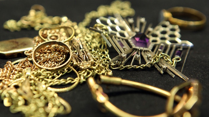 Symbolbild: Goldschmuck liegt auf einem schwarzen Untergrund.