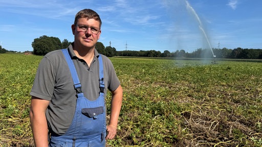 Ein Mann mit Brille und braunen Haaren steht in einem Feld