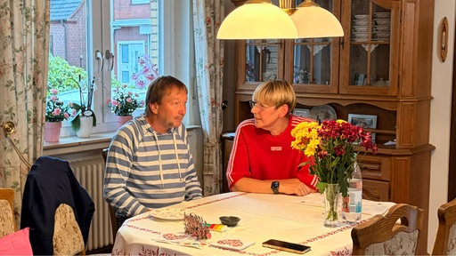 Der Mann und seine Frau sitzen am Esstisch.