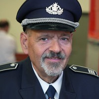 Dieter Krawitz schaut in seiner Uniform in die Kamera und im Hintergrund steht ein Feuerwehrwagen.