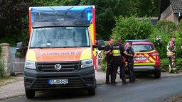 Rettungskräfte der Feuerwehr und Polizei stehen vor dem Grundstück, auf dem der Mann absackte.