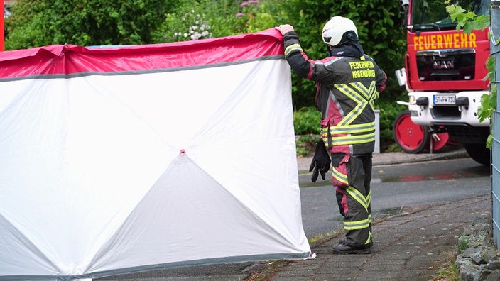 Ein Mann von der Feuerwehr hält einen Sichtschütz am Einsatzort