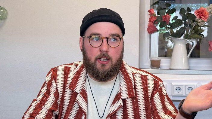 Ein Mann mit Bart und Brille spricht.