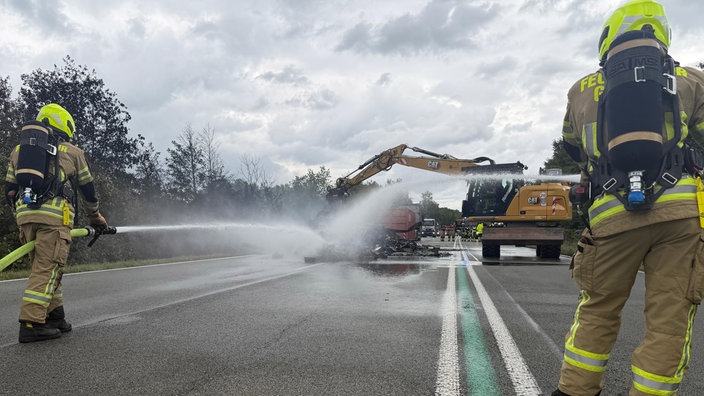 Feuerwehrleute löschen qualmende Wrackteile