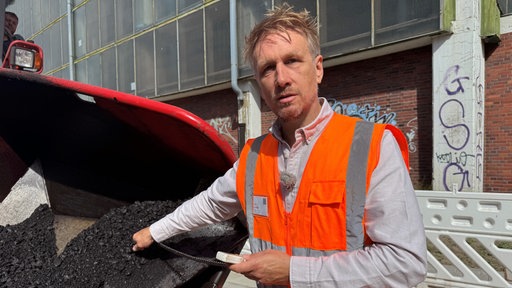 Firmenchef Maik Gieseke misst die Asphalt-Temperatur. 