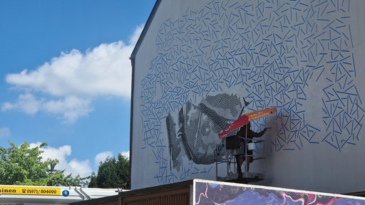 Ein Künstler malt Streetart auf eine Hauswand in Rheine