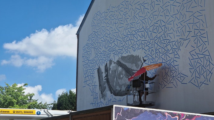 Ein Künstler malt Streetart auf eine Hauswand in Rheine