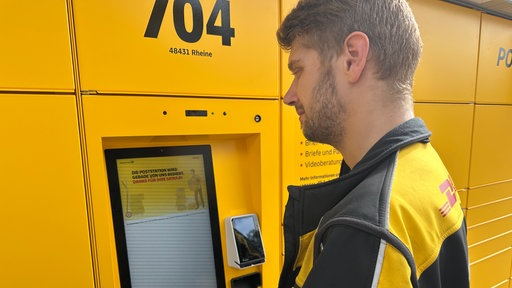 Postzusteller Maurice Pape steht vor der neuen Poststation am Bedienterminal.