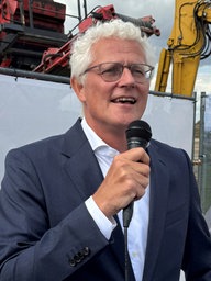 Geberit-Chef Christian Buhl steht vor einem Bau Zaun und spricht in ein Mikrofon.