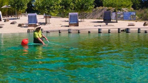 Schwimmbadmitarbeiterin mit Fischerhose im Naturbad Ennigerloh mit Kescher