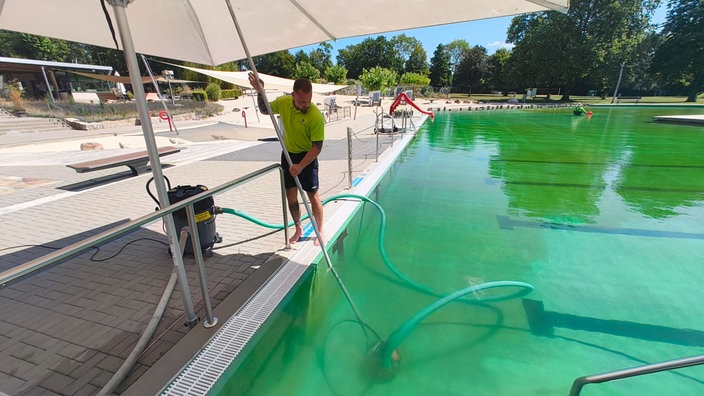 Schwimmeister am Beckenrand mit Reinigungsroboter