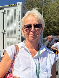 Eine Frau mit Sonnenbrille steht vor einem der Großbatteriespeicher