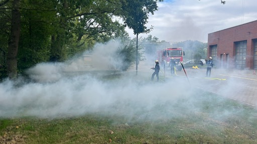 Feuerwehrmänner testen das neue Löschfahrzeug, indem sie ein kleines Feuer am Wegesrand löschen.