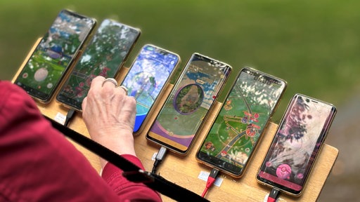 Sechs Handys auf einem Brett, auf denen Pokemon geöffnet ist.