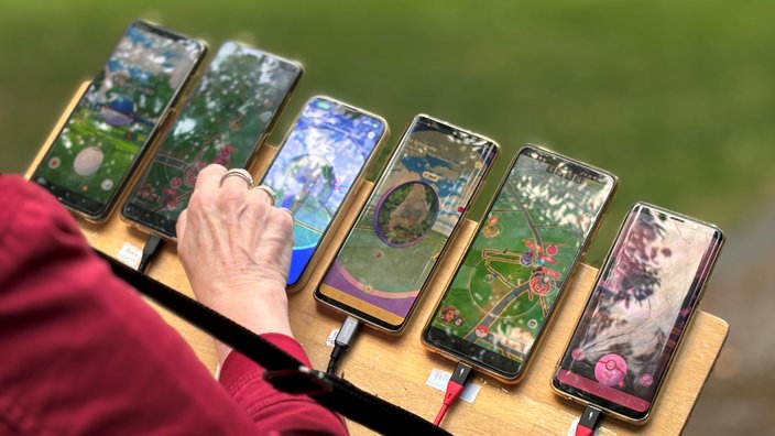 Sechs Handys auf einem Brett, auf denen Pokemon geöffnet ist.
