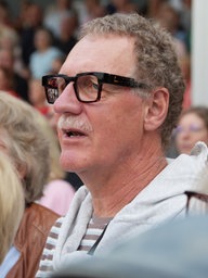 Ein Besucher mit dicker Hornbrille und Schnauzbart singt laut mit.