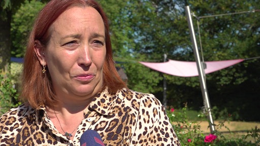 Tanja Vrenken mit einem gemusterten Kleid und rötlichen Haaren.