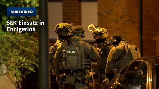 SEK-Beamte stehen in voller Ausrüstung im Kreis bei Nacht; dazu die Schrift "Kurzvideo: SEK-Einsatz in Ennigerloh.
