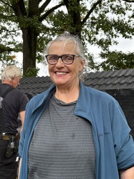 Eien Frau steht vor einem Dach mit Solarpanel und grinst in die Kamera