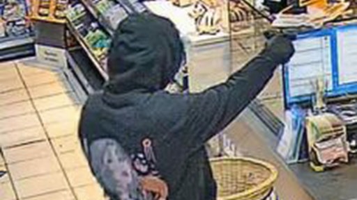 Vermummter Mann mit einem schwarzem Hoodie und einer Pistole.