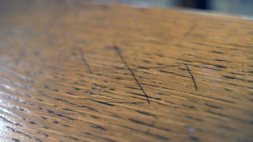 Ein Hakenkreuz in eine Kirchenbank geritzt.