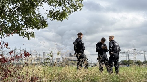 Drei Polizisten stehen auf einem Feld in Weisweiler.