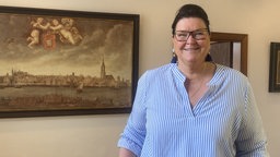 Eine brünette Frau mit Brille schaut in die Kamera.