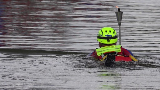 Ein DRK-Schwimmer im Wasser mit einer Fackel 