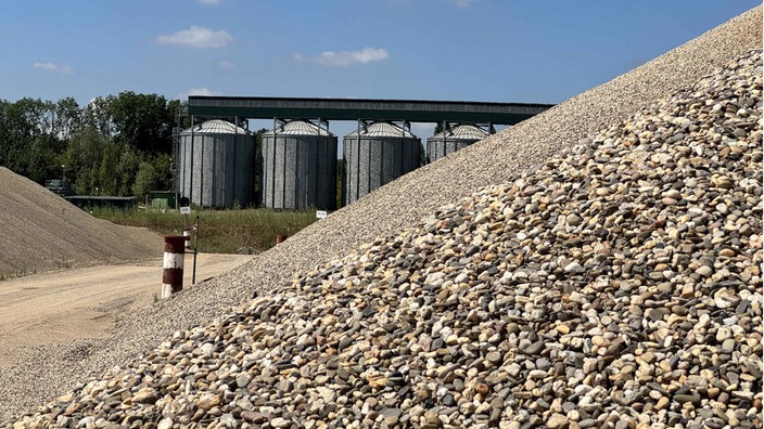 Ein Kiesberg, im Hintergrund Silos. Das Kieswerk Ellerdonk der Firma Holemans in Wesel
