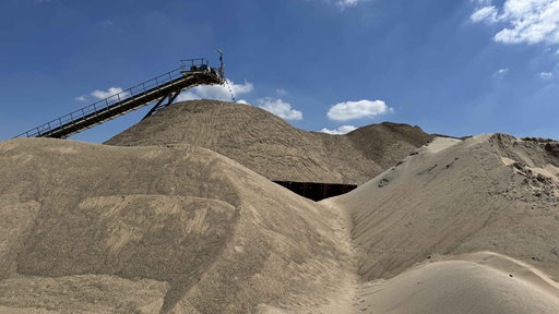 Ein Förderband befördert Kies auf einen großen Kieshügel im Kieswerk Ellerdonk der Firma Holemans in Wesel