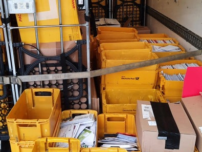 Gelbe Postkisten voller Briefe und Pakete stapeln sich in einem Lastwagen