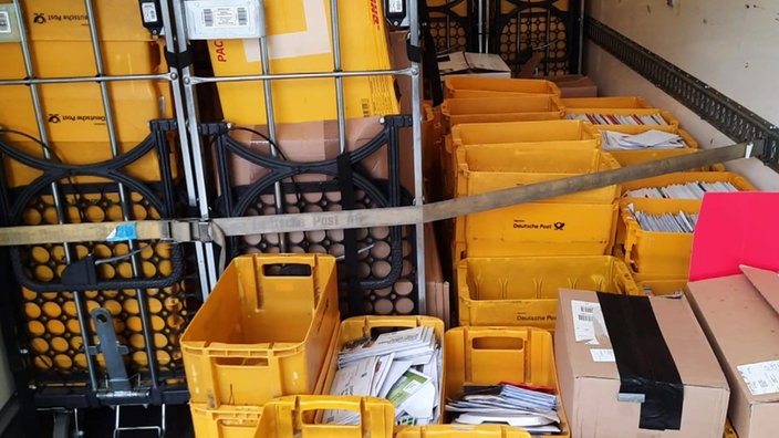 Gelbe Postkisten voller Briefe und Pakete stapeln sich in einem Lastwagen