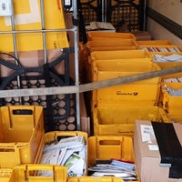 Gelbe Postkisten voller Briefe und Pakete stapeln sich in einem Lastwagen