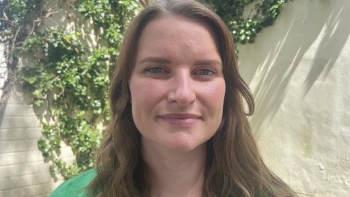 Julia Stratmann, in grünem T-Shirt vor einer Hecke vom BUND 